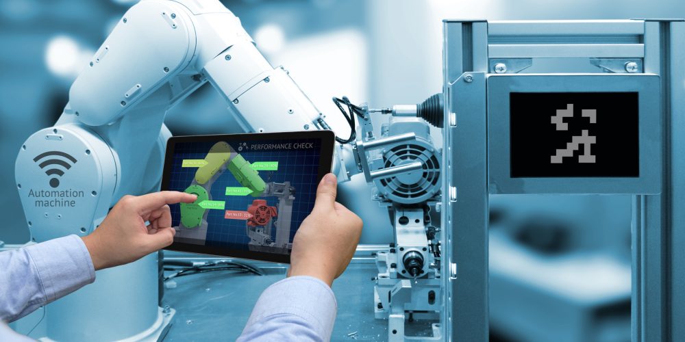 Industry 4.0 concept . Man hand holding tablet with performance check screen software and blue tone of automate wireless Robot arm in smart factory background